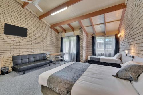 een slaapkamer met een groot bed en een bakstenen muur bij Snobs Creek Motel Eildon in Eildon