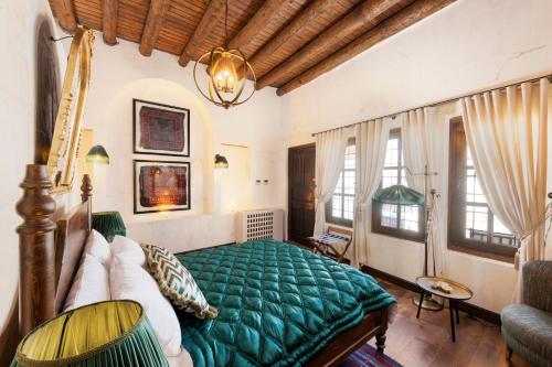 een slaapkamer met een groen bed in een kamer met ramen bij Zerzembe Boutique Hotel in Sanlıurfa