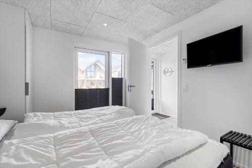 une chambre blanche avec un lit et une télévision à écran plat dans l'établissement 917-Hvide-Sande-Langsand-176-stuen, à Hvide Sande