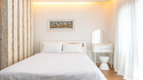 ein weißes Schlafzimmer mit einem weißen Bett und einem Fenster in der Unterkunft Ganghwa Hanabi Pension in Incheon