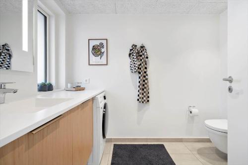 een witte badkamer met een wastafel en een toilet bij 908-Hvide-Sande-Langsand-102-stuen in Hvide Sande