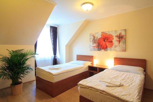 a room with two beds and a plant in it at Penzion U Čejpu in Prague