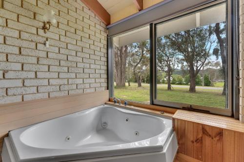 een wit bad in een kamer met een raam bij Snobs Creek Motel Eildon in Eildon