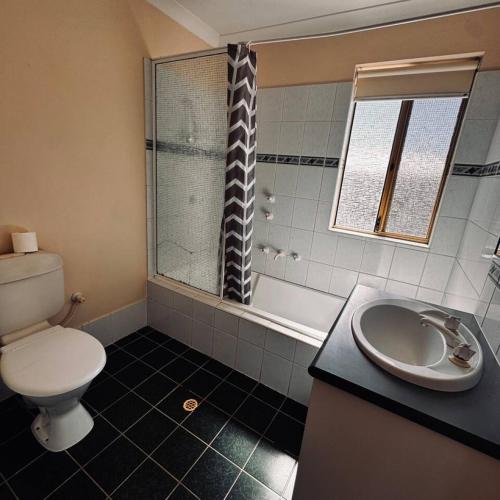 a bathroom with a toilet and a sink and a shower at Live, Laugh, Lodge - Central 3x2 in Kalgoorlie