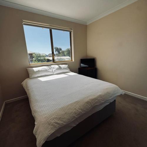 a bedroom with a large bed with a window at Live, Laugh, Lodge - Central 3x2 in Kalgoorlie