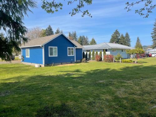 a blue house in a yard with a grass field at Bogachiel Den in Forks
