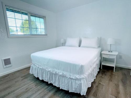 a white bedroom with a large bed and a window at The Sitka Spruce House in Forks