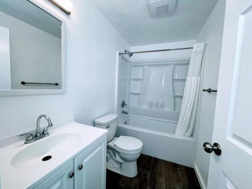 a white bathroom with a toilet and a sink at The Sitka Spruce House in Forks