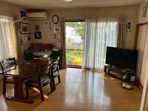 ein Wohnzimmer mit einem Esstisch und einem TV in der Unterkunft Okegawa Quiet Homestay in Okegawa