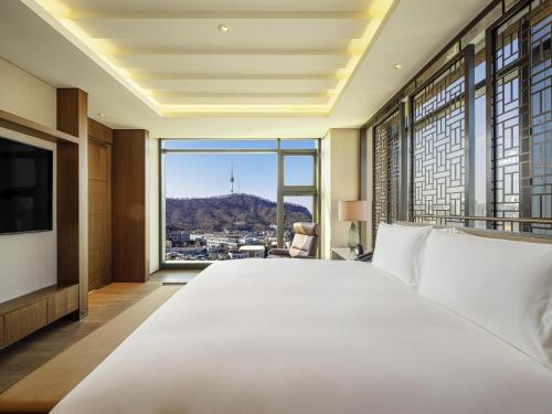ein Schlafzimmer mit einem großen weißen Bett und einem großen Fenster in der Unterkunft The Ambassador Seoul - A Pullman Hotel in Seoul