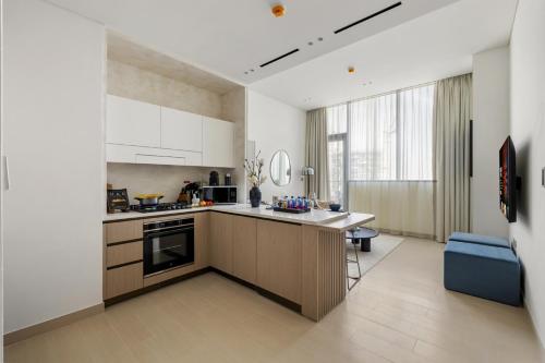 a kitchen with white cabinets and a blue couch at Stylish 1BR with Private Pool Near Circle Mall in Dubai