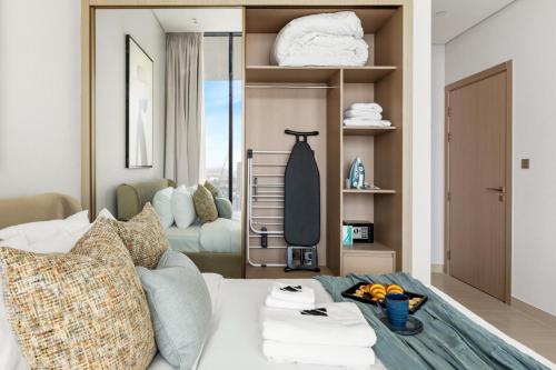 a room with a bed with towels on a shelf at Stylish 1BR with Private Pool Near Circle Mall in Dubai
