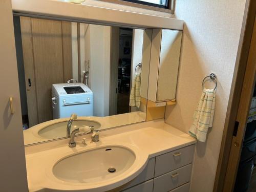 ein Badezimmer mit Waschbecken und Spiegel in der Unterkunft Okegawa Quiet Homestay in Okegawa