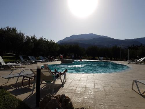 a person laying in a chair next to a swimming pool at Casale La Macina - Hotel, Scopello in Scopello