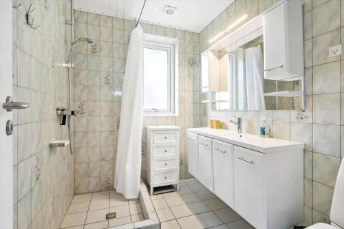 een witte badkamer met douche en wastafel bij S718-Stroby-Svalemosevej-18 in Strøby