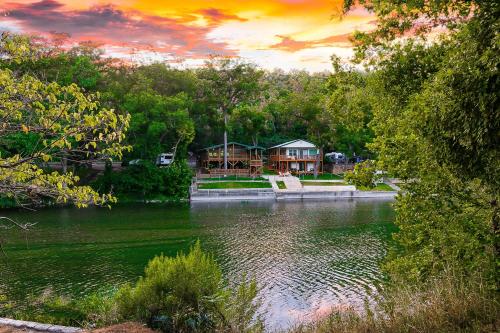 een huis aan de oever van een meer met een zonsondergang bij Riverfront Getaway On Guadalupe River in New Braunfels
