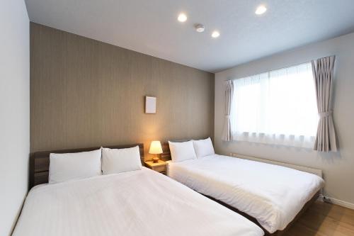 two beds in a small room with a window at 東川Hinna in Higashikawa
