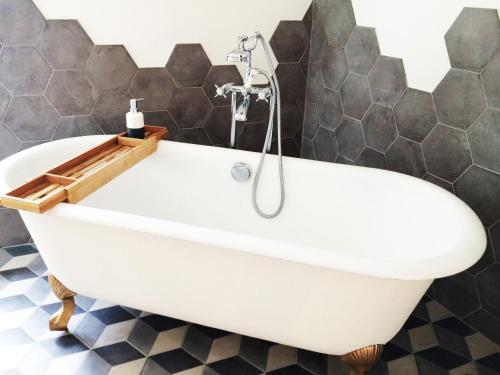 een wit bad in een badkamer met zwarte tegels bij Hortensias in La Croix-Helléan