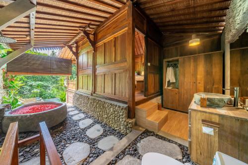 a bathroom with a tub in a room with wooden walls at Saughina Ubud in Ubud