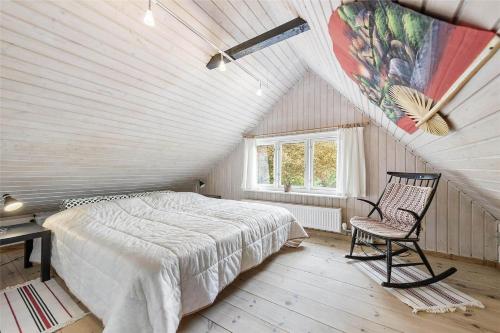 een slaapkamer met een bed en een stoel op zolder bij FA009-Faxe-Ladeplads-Brandskov-6 in Fakse Ladeplads