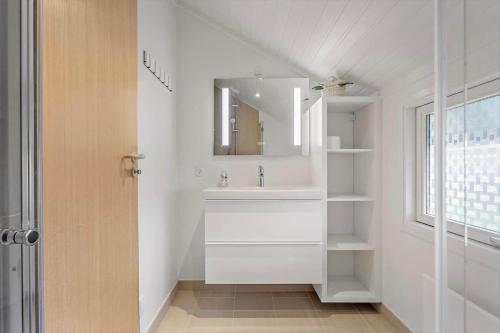 a white bathroom with a sink and a mirror at 3078-Stege-Maegleren-18 in Stege
