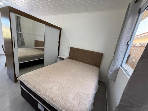 een kleine slaapkamer met een bed en een spiegel bij Loft novo e bem localizado in Biguaçu
