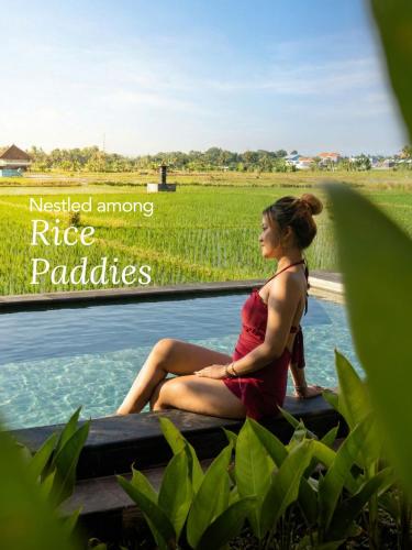 eine Frau in einem roten Kleid sitzt im Wasser in der Unterkunft Kalyana Gangga in Krambitan