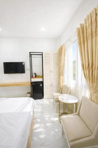a white room with a bed and a table and chairs at Đại Phú Hotel Hồ Chí Minh in Ho Chi Minh City