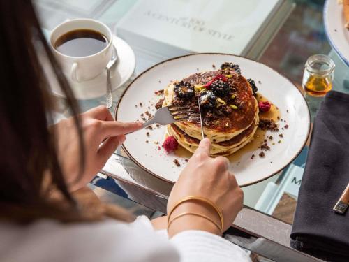 Eine Frau isst mit einer Gabel einen Teller Pfannkuchen. in der Unterkunft Sofitel Chicago Magnificent Mile in Chicago