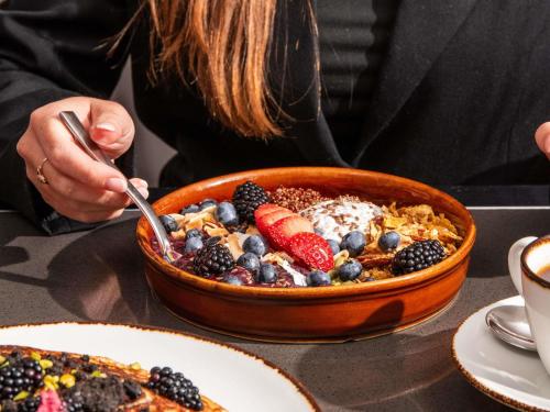 eine Frau sitzt an einem Tisch mit einer Schüssel Frühstücksessen in der Unterkunft Sofitel Chicago Magnificent Mile in Chicago
