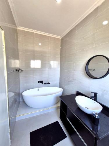 a bathroom with a tub and a sink and a mirror at 2nd street ibex Apartment in Lusaka