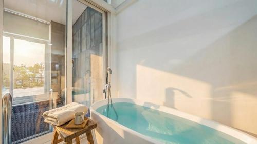 un bagno con una grande vasca con finestra di Goseong Belloci Kids Poolivilla a Goseong