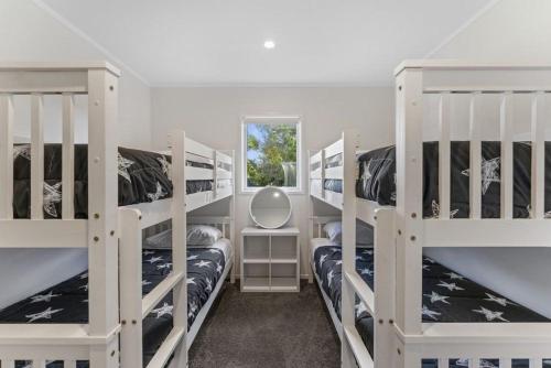 ein Zimmer mit drei Etagenbetten und einem Fenster in der Unterkunft Modern Lake View House in Mangakino