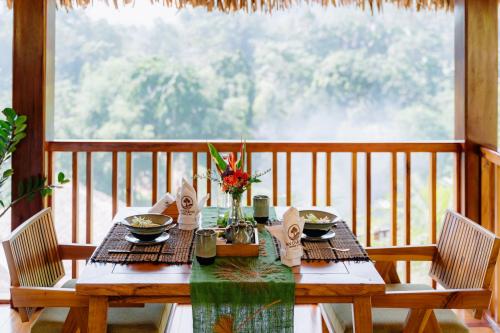 einen Holztisch mit Tellern und Blumen auf dem Balkon in der Unterkunft An Station - Dorm & Onsen packaged in Ha Giang