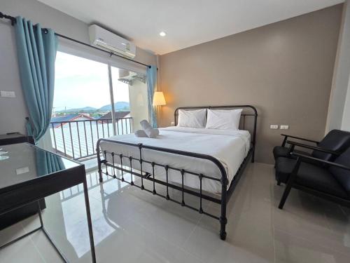 a bedroom with a bed and a desk and a balcony at Khao Oat airport in Nai Yang Beach