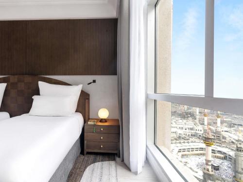 ein Schlafzimmer mit einem Bett und einem großen Fenster in der Unterkunft Zamzam Pullman Makkah in Mekka