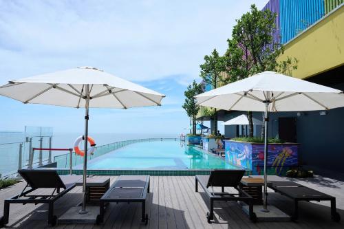 Nam KhêFlamingo Hai Tien的两把白色遮阳伞坐在游泳池旁