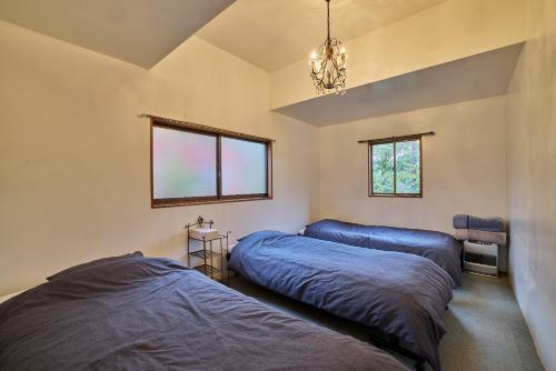 a bedroom with two beds and a chandelier at Casa Allegra in Yamanakako