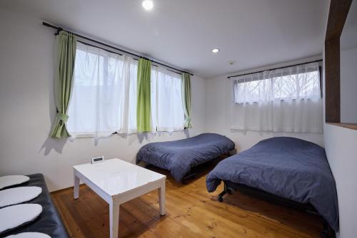 a room with two beds and a table and windows at Casa Allegra in Yamanakako