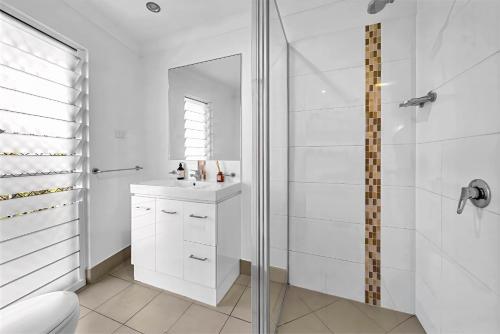un bagno bianco con doccia e lavandino di Panoramic Oceanview Villa a Bowen