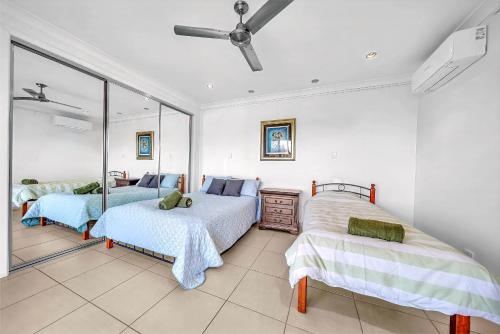 una camera da letto con due letti e un ventilatore a soffitto di Panoramic Oceanview Villa a Bowen