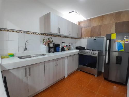 a kitchen with white cabinets and a stainless steel refrigerator at Suite cerca de la UTPL y Centro Histórico in Loja