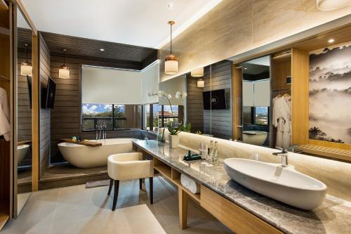 a bathroom with a tub and a sink and a tub and a bath tub at The Manohara Hotel Yogyakarta in Yogyakarta