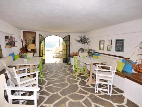 un comedor con mesas blancas y sillas verdes en Villa Belmar Self-Catered Apartments, en Eretria
