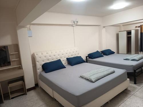 2 letti con cuscini blu in una stanza di Doctor Thanut Hostel a Ubon Ratchathani