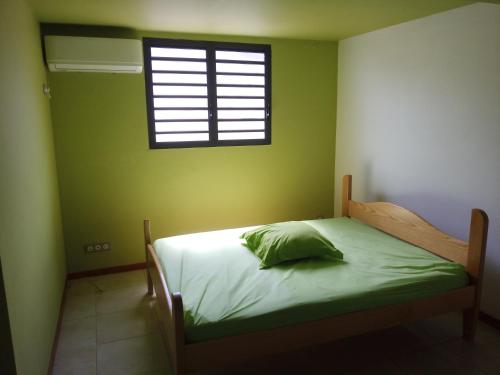 een groene slaapkamer met een bed en een raam bij kaz a gabou in Sainte-Rose