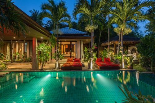 a swimming pool in front of a house with palm trees at Villa Samprasada in Bophut 