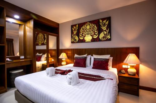 a bedroom with two beds with white sheets and red pillows at Huen Jao Ban Hotel in Chiang Mai