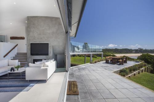 un salon avec un canapé blanc et une télévision dans l'établissement Bawley Point Beach Front - oceanfront luxury home, à Bawley Point