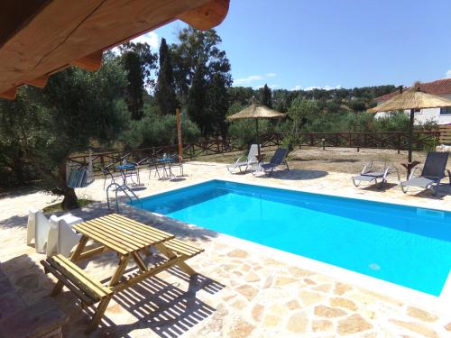 a swimming pool with chairs and a table next to it at Alegria Villas Complex in Vasilikos